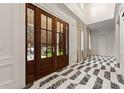 Grand foyer showcasing custom millwork, black and white marble floors, and a stunning front door with decorative glass at 3488 Tuxedo Nw Rd, Atlanta, GA 30305