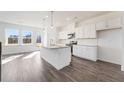 Modern kitchen boasts an island, stainless appliances, ample natural light, and stylish gray wood flooring at 3267 Durston Ct, Dacula, GA 30019