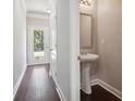 Hallway leading to a powder room with pedestal sink, mirror, and hardwood flooring at 3102-A Brownstone Se Ln, Atlanta, GA 30354
