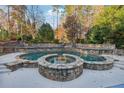 Beautiful outdoor retreat with stone-accented pool and hot tub surrounded by lush landscaping at 2195 Lake Shore Lndg, Alpharetta, GA 30005