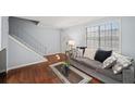 Inviting living room with hardwood floors, a gray sofa with decorative pillows, and a stairway at 2946 N Dekalb Dr # Apt C, Atlanta, GA 30340