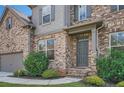 Close up of a brick house with gray front door, trimmed bushes, and two car garage on the left at 207 Eagles Flight, Villa Rica, GA 30180