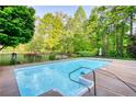 Sparkling pool surrounded by lush landscaping, creating a serene and private backyard oasis at 110 Cove Ln, Social Circle, GA 30025