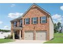 Two-story brick home with a two-car garage, complemented by shuttered windows and a well-maintained lawn at 1363 Midnight Ride Ct, Hampton, GA 30228