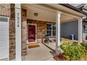 Inviting front porch with brick columns, seating and a bright red door at 7214 Gladstone Cir, Stonecrest, GA 30038