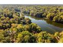 Aerial view of house on lakefront property surrounded by lush trees at 8316 Hewlett Rd, Sandy Springs, GA 30350