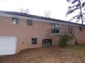 The rear exterior of a brick home with a garage and a small balcony area accessed by a sliding glass door at 3685 Emily Way, Atlanta, GA 30349