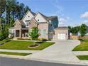 Brick two-story house with stone accents, three-car garage, and landscaped lawn at 1927 Streamlet Xing, Kennesaw, GA 30152