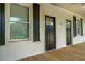 Spacious covered front porch showcasing a double entry, shutters, and wood flooring at 31 N Broad N St, Porterdale, GA 30014