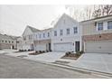 View of townhomes with modern gray brick, one-car garages, and inviting entrances at 695 Sunstone Ln, Lawrenceville, GA 30043