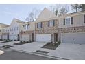 A row of townhomes featuring brick and siding, each with a garage and landscaping at 691 Sunstone Ln, Lawrenceville, GA 30043