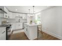 Modern white kitchen with island, stainless steel appliances, and hardwood floors at 599 Quillian Ave, Decatur, GA 30032