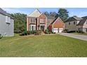 Brick two-story house with a three-car garage and manicured lawn at 1721 Telfair Chase Way, Lawrenceville, GA 30043