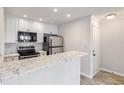 Kitchen featuring white cabinets, stainless steel appliances and breakfast bar with marble countertops at 201 Granville Ct, Atlanta, GA 30328