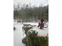 Snow covered garden with plants and Buddha statue at 3554 Umatilla Sw Ln, South Fulton, GA 30331