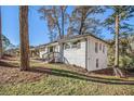Exterior view of a single-story white brick home with mature trees and a well-manicured lawn at 1723 Capistrana Pl, Decatur, GA 30032