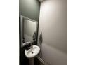 A modern powder room featuring a pedestal sink, gray framed mirror, and stylish dark green accent wall at 253 Ivey Ter # 48, Temple, GA 30179