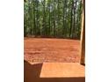 A view of the construction area in the backyard with mature trees and red clay soil at 542 Palm St, Holly Springs, GA 30115