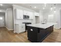 Modern kitchen with black island, quartz countertops, stainless steel appliances, and stylish pendant lighting at 913 Agate Ln, Lawrenceville, GA 30043