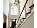 Grand foyer featuring a chandelier, large arched window, and a front door with decorative glass panels at 4511 Balmoral Nw Rd, Kennesaw, GA 30144