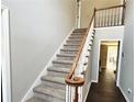 Carpeted staircase with a classic wooden handrail leading to the second floor of the home at 4511 Balmoral Nw Rd, Kennesaw, GA 30144