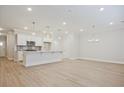 Bright, open-concept living space with modern lighting fixtures and a kitchen island featuring stainless appliances at 905 Agate Ln, Lawrenceville, GA 30043