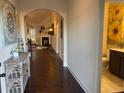 Hallway featuring hardwood floors, neutral walls, arched doorways, and a glimpse of the living room at 1124 Kingston Hill Dr, Loganville, GA 30052
