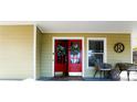 Inviting front porch with double red doors, wreaths, rocking chairs, and a decorative wooden 'R' at 180 Paula Dr, Tyrone, GA 30290