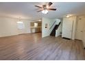 Open-concept living space with new laminate flooring, ceiling fan, and view of the kitchen and staircase at 3648 E Melissa Ln, Douglasville, GA 30135