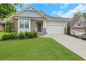 Charming home featuring stone accents, blue siding, well-manicured landscaping, and a two-car garage at 413 Solace Pl, Canton, GA 30114