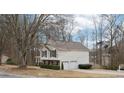 Well-maintained home featuring a two-car garage and a neatly kept lawn, highlighted by mature trees on a sunny day at 2965 Ivy Mill Dr, Buford, GA 30519