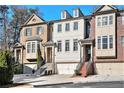 Three story townhomes featuring attached garages, front staircases, and a mixture of brick and painted exteriors at 3693 Broughton Se Cir, Atlanta, GA 30339