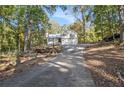 A long driveway leads to this two-story home with a two-car garage and metal roof, surrounded by trees at 34 Clay Ct, Villa Rica, GA 30180