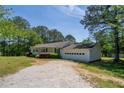 View of the side of a single-story home with a two-car garage, a gravel driveway and landscaped lawn at 2334 Highway 278, Social Circle, GA 30025