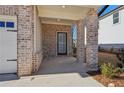 Covered front porch with brick columns and a gray door at 4755 Marjorie Dr, Cumming, GA 30041