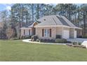 Brick home with a 2-car garage, wooden shutters, manicured landscaping, and a sidewalk leading to the front door at 1250 Olympic Dr, Oxford, GA 30054