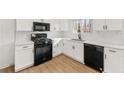 Modern kitchen featuring white cabinets, sleek black appliances, and beautiful quartz countertops at 708 Martin Rd, Stone Mountain, GA 30088