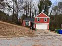 A red two-story home with a two-car garage, complemented by a cozy front yard at 7472 Wood Ct, Lithonia, GA 30058