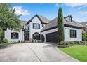 Striking two-story home with arched windows, two-car garage, dark trim, and a well-manicured lawn at 220 Windsor Gate Ne Cv, Atlanta, GA 30342