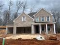 New brick home featuring a three-car garage and classic white column front porch at 6945 Melody Dr, Buford, GA 30518