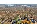 An aerial view of a luxury home nestled amidst lush trees and near a serene lake, offering privacy at 5705 Windjammer Pt, Cumming, GA 30041