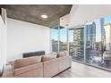 Living room showing large windows with city views, hardwood floors, and tan sectional couch at 3324 Peachtree Ne Rd # 1503, Atlanta, GA 30326