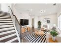 Bright living room with modern decor, including a striped rug, plants, and an adjacent staircase at 434 Herring Dr, Acworth, GA 30102