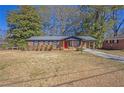 Charming red brick home with a well-maintained lawn and a carport featuring an orange front door at 5380 Saint Lo Ln, Atlanta, GA 30349