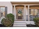 Inviting front porch featuring a decorative wreath on the front door and elegant column supports at 5975 Deerwoods Trl, Alpharetta, GA 30005