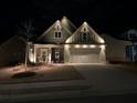 Charming home exterior with beautiful lawn and landscaping illuminated at night at 595 Everton Pl, Grayson, GA 30017