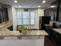 Kitchen boasting stainless steel appliances, dark cabinetry, granite countertops, and a well-lit dining area at 1957 Paxton Sw Dr, Lilburn, GA 30047