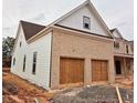 View of the attached garage and side elevation, with brick and shingle details on this new home at 1937 Pucketts Sw Dr, Lilburn, GA 30047