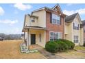Townhouse with a covered porch, brick and vinyl siding, complemented by lush green bushes at 1450 Riverrock Trl, Riverdale, GA 30296