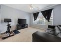 Cozy living room with a ceiling fan, plush carpeting, and large windows offering plenty of natural light at 1450 Riverrock Trl, Riverdale, GA 30296